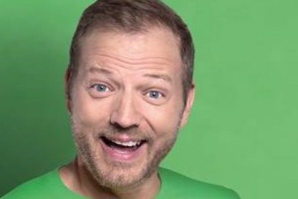Mario Barth in front of a green background, smiling into the camera